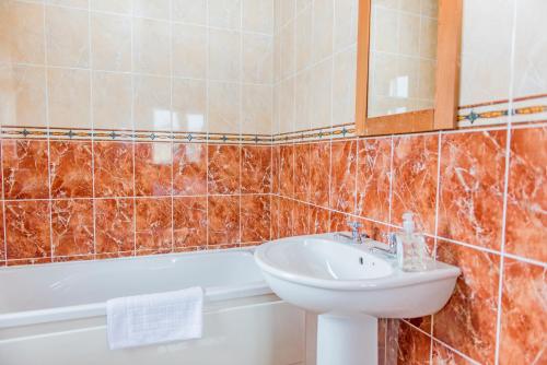 a bathroom with a sink and a toilet and a tub at Duncarbury Heights - 4 Bedroom Detached House in Tullaghan