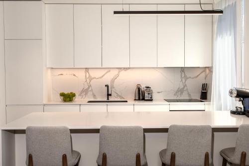 a kitchen with white cabinets and a counter with chairs at Petram Resort & Residences in Savudrija