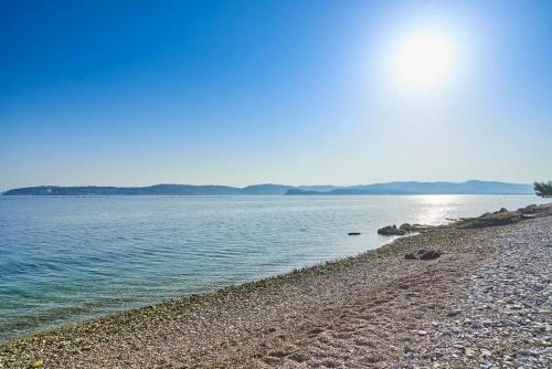 a rocky beach with the sun shining on the water at Villa Ventana with terrace and BBQ in Savudrija