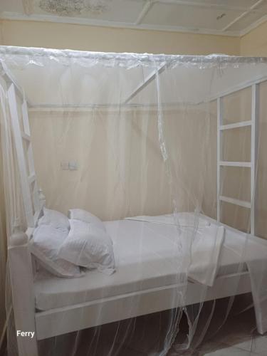 a white bed with a canopy in a room at Ferry homes in Watamu