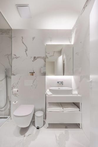 a white bathroom with a toilet and a sink at Petram Resort & Residences in Savudrija