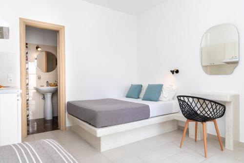 a white bedroom with a bed and a chair at Depis place & apartments naxos in Naxos Chora