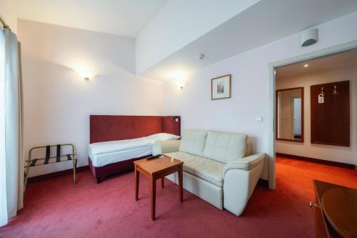 a hotel room with a couch and a bed at Hotel Raffaello Prague in Prague