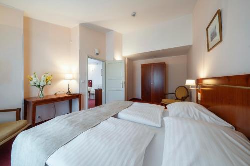 a bedroom with a large bed with white sheets at Hotel Raffaello Prague in Prague