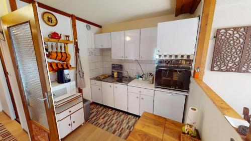 eine Küche mit weißen Schränken und einem Herd mit Backofen in der Unterkunft Escapade Familiale en Montagne in Métabief