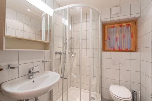a white bathroom with a sink and a shower at Chalet Capricorn in Bettmeralp