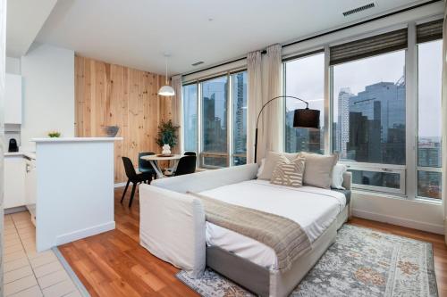 a bedroom with a white bed and large windows at Chic Downtown Apartment with City Views near Stanley Park in Vancouver
