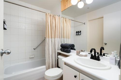 a bathroom with a sink and a toilet and a tub at Chic Downtown Apartment with City Views near Stanley Park in Vancouver