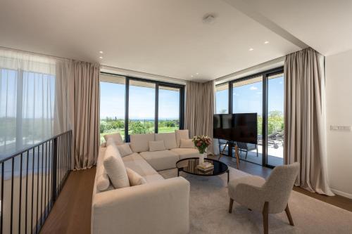 a living room with white furniture and large windows at Petram Resort & Residences in Savudrija