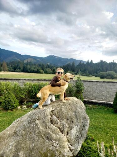 a man and a dog sitting on a rock at Apartmán pod Sivým vrchom in Zuberec