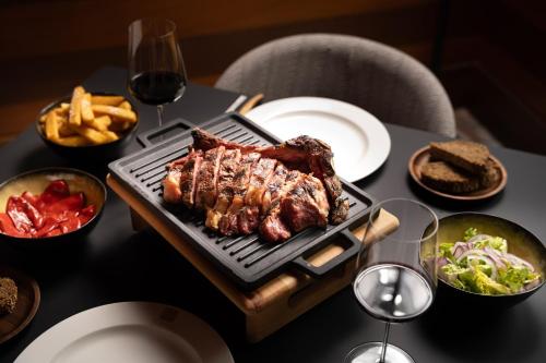 a table with a grill with meat and french fries at Hotel Meliá Bilbao in Bilbao