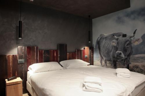 a bedroom with a large bed with a cow on the wall at Crimea Wine Hotel in Chiavenna