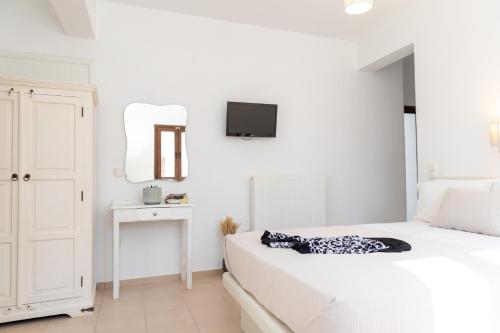a white bedroom with a bed and a tv on the wall at Depis place & apartments naxos in Naxos Chora