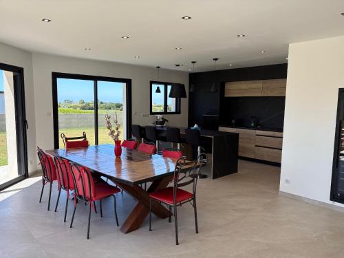 une salle à manger avec une table en bois et des chaises rouges dans l'établissement Maison neuve 4 chambres, à Cléder