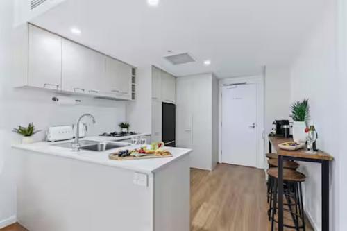 a white kitchen with a sink and a counter at Elevate Brisbane City - Views, Pool, Sauna & Gym in Brisbane
