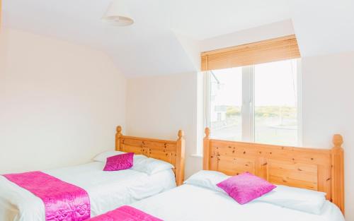 two twin beds in a room with a window at Duncarbury Heights - 4 Bedroom Detached House in Tullaghan