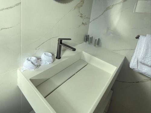 a white bathroom with a sink and a faucet at 19 On BayNoakes Boutique in Harare