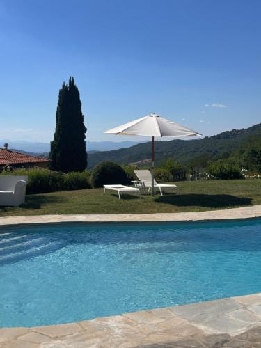 a white umbrella and a chair and a table and a pool at Resort con vista nel Chianti Rufina in Londa