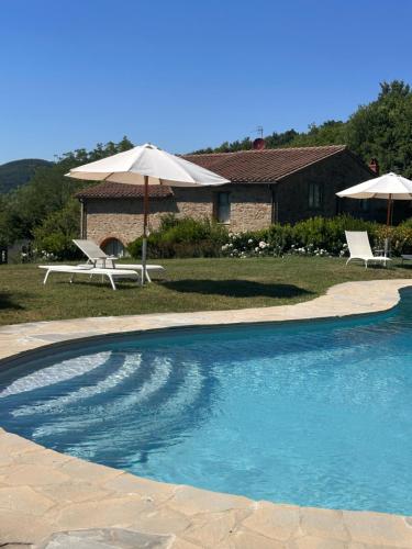 a swimming pool with two chairs and an umbrella at Resort con vista nel Chianti Rufina in Londa
