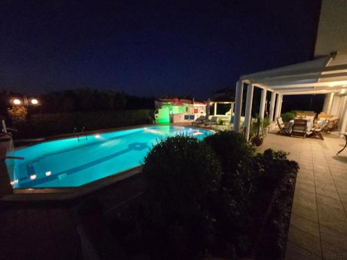a swimming pool at night with a house at Elia Apartment in Paralion astros