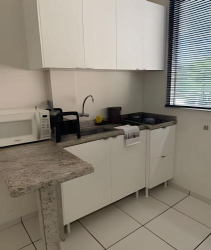 eine Küche mit weißen Schränken und einer Mikrowelle in der Unterkunft Apto funcional e bem equipado in Maringá