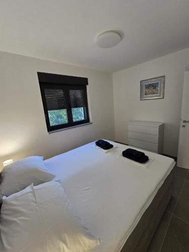 a bedroom with a large white bed with a window at Apartment Lumiere in Ljubuški