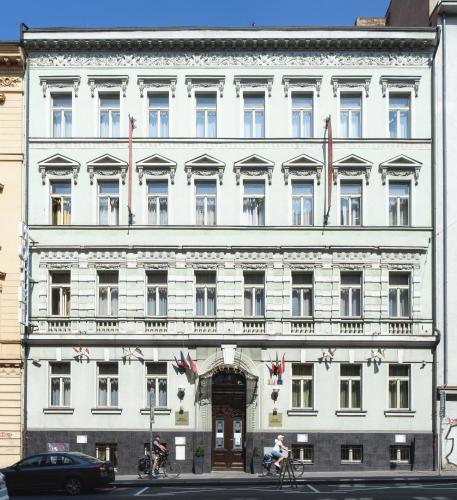a large white building with people riding bikes in front of it at Hotel Raffaello Prague in Prague