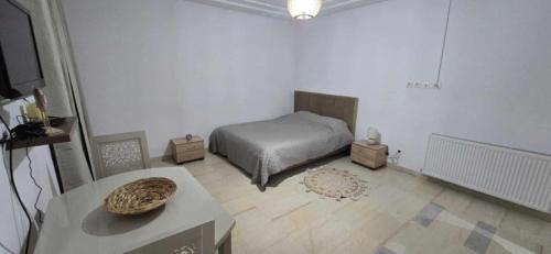 ein weißes Zimmer mit einem Bett und einem Tisch in der Unterkunft Oumaima in Sidi Daoud