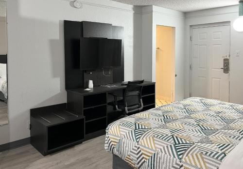 a bedroom with a bed and a desk with a television at Studio 6 Suites Dayton OH Englewood in Dayton