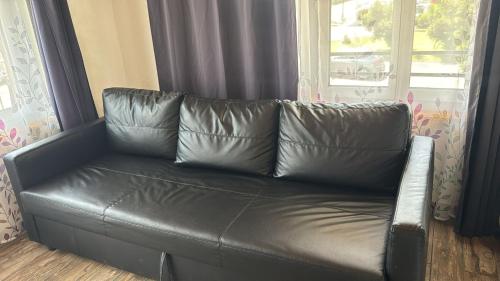 a leather couch in a living room with a window at Swiss Chalet Holidays Ringgenberg in Ringgenberg