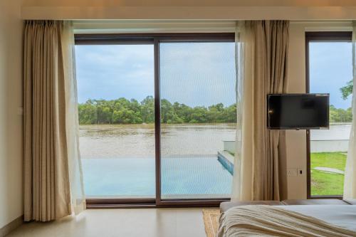 a bedroom with a large window with a view of a lake at Villa Fleuve 6-BHK Riverfront Hideaway With Infinity Pool & Bathtub in Nerul