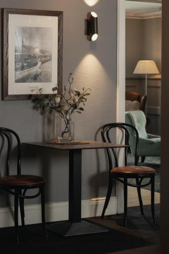 a table with two chairs and a vase with flowers on it at Home Hotel Uman in Umeå