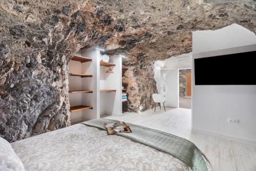 una camera da letto in una grotta con un letto e una TV di Luxury Home la Cueva del Guanche ad Adeje