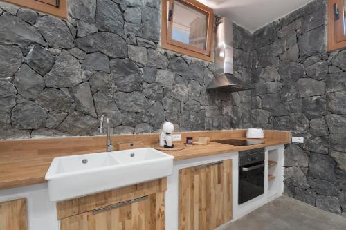 una cucina con lavandino e parete in pietra di Luxury Home la Cueva del Guanche ad Adeje