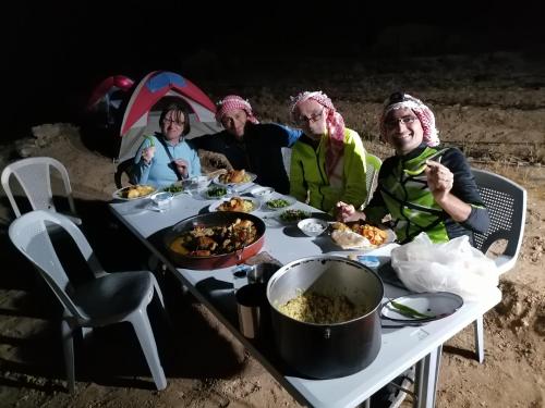 a group of people sitting around a table with food at Tafila-Mataan in Al Jafr