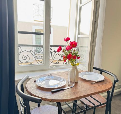 une table avec deux assiettes et un vase de fleurs sur une fenêtre dans l'établissement Studio B2 - Centre-Ville Meaux - Proche Disneyland, à Meaux