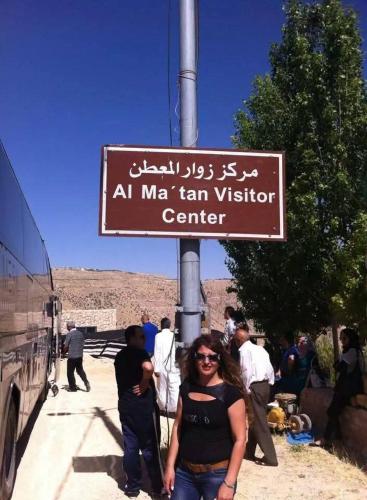 a woman standing under a sign in front of a bus at Tafila-Mataan in Al Jafr