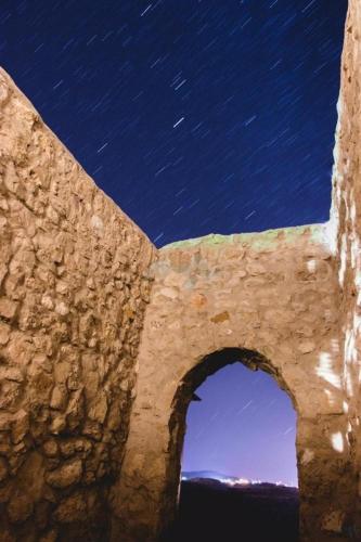 a stone wall with an arch under a night sky at Tafila-Mataan in Al Jafr