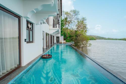 a swimming pool with a view of the water at Villa Fleuve 6-BHK Riverfront Hideaway With Infinity Pool & Bathtub in Nerul