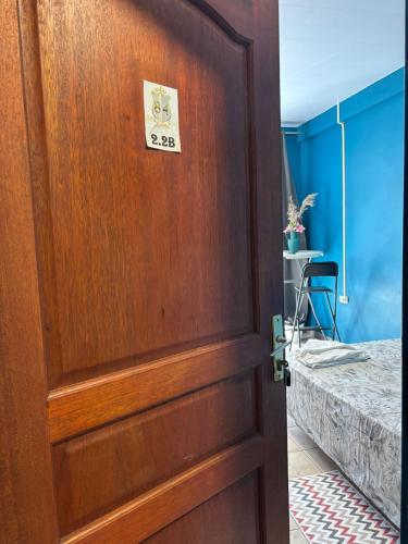 a wooden door with a clock on it next to a bed at 84Rooms in Cayenne