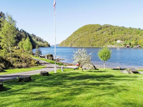 a grassy area with a lake in the background at Holiday Home Naudøyna by Interhome in Lyngdal