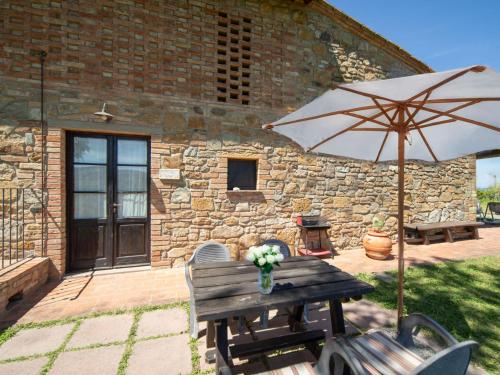 a wooden table with an umbrella and some chairs at Apartment Giotto by Interhome in Montaione