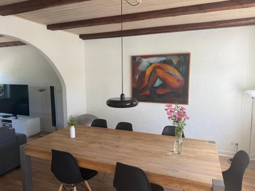 a dining room with a wooden table and a painting at Hus ved Svendborg in Svendborg