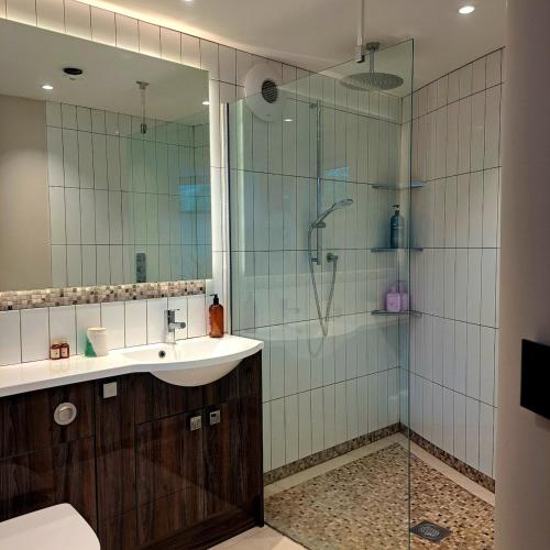a bathroom with a glass shower with a sink and a toilet at The Shutter House in Compton