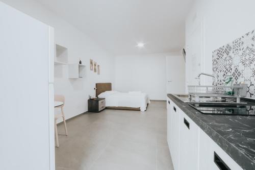a white kitchen with a sink and a bed at Noah&Chris Apartments in Bitritto