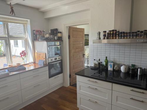 a kitchen with white cabinets and a black counter top at Hus ved Svendborg in Svendborg
