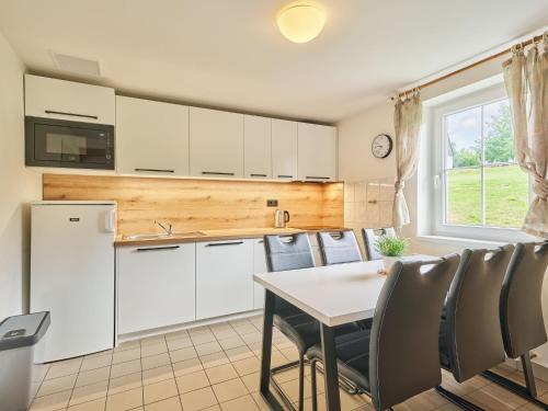 eine Küche mit weißen Schränken und einem Tisch und Stühlen in der Unterkunft Holiday Home Holiday Hill 45 by Interhome in Lauterwasser