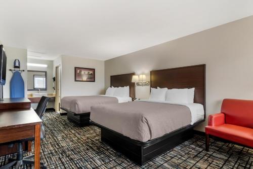 a hotel room with two beds and a red chair at Quality Inn & Suites I-10 near Fiesta Texas in San Antonio
