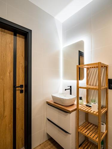 a bathroom with a sink and a wooden shelf at Pod Lasem Apartamenty in Łukęcin