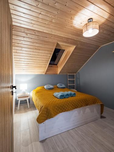 a bedroom with a bed with a wooden ceiling at Pod Lasem Apartamenty in Łukęcin